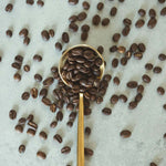 Luna Nueva specialty-grade Mexican coffee beans on gold spoon with scattered beans on marble background