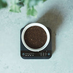 Ground coffee in white container on digital scale showcasing Synastry blend with Colombian and Ethiopian beans
