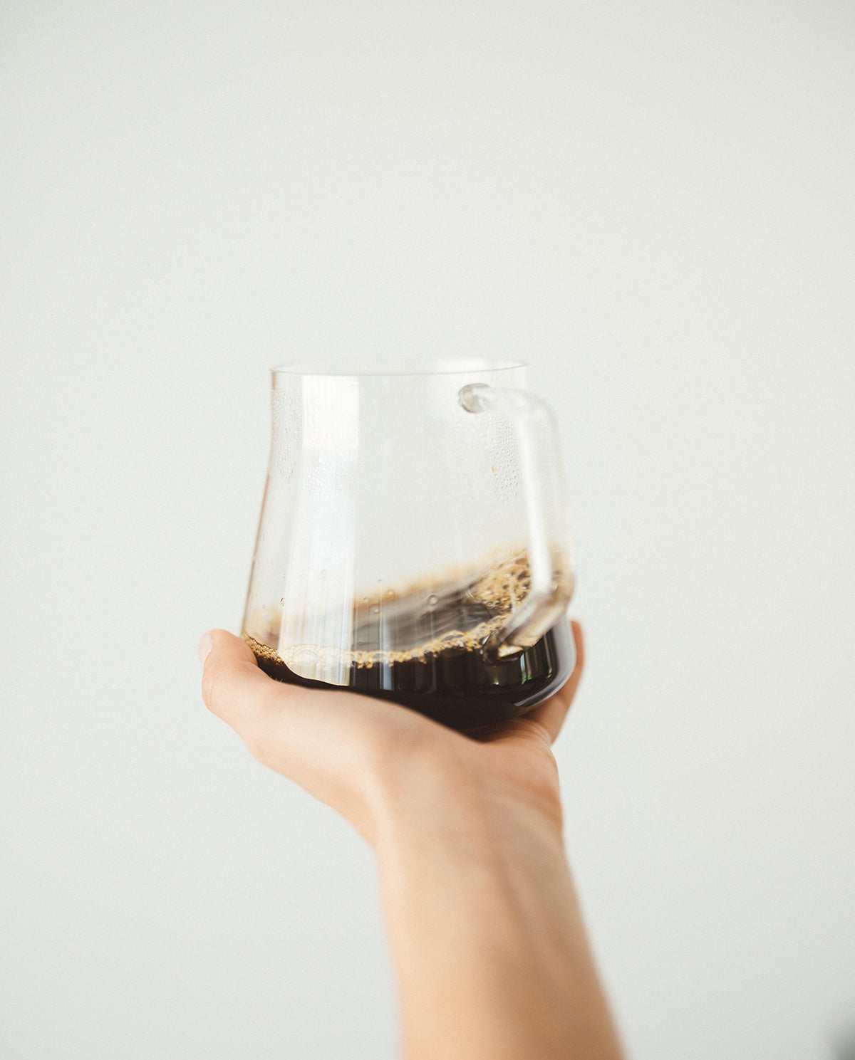 Hand holding a clear glass cup filled with Luna Nueva specialty coffee, showcasing a smooth, full-bodied Mexican coffee.
