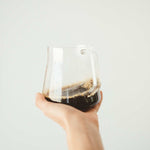 Hand holding a clear glass cup filled with Luna Nueva specialty coffee, showcasing a smooth, full-bodied Mexican coffee.